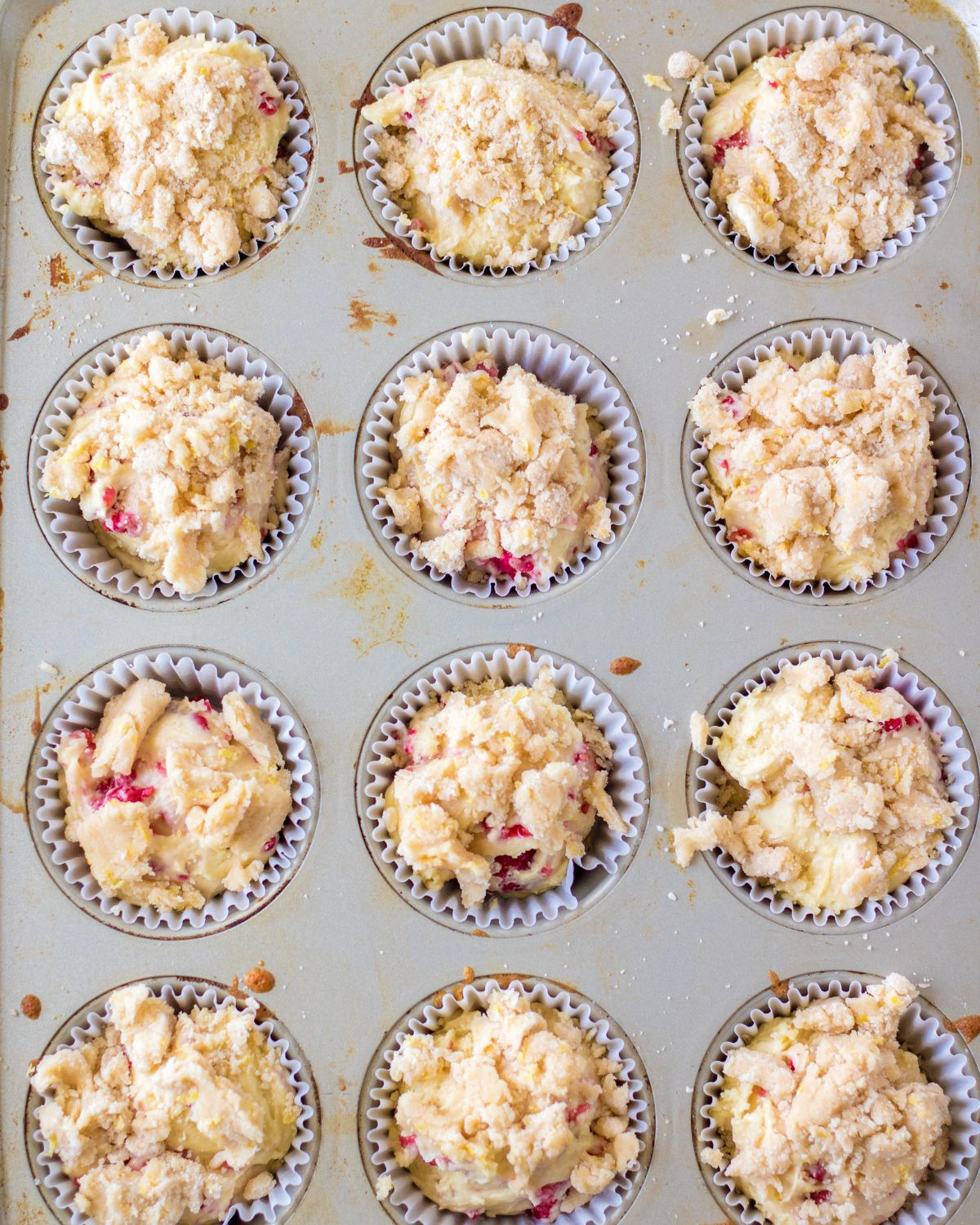 A muffin tin with raspberry lemon muffin batter.