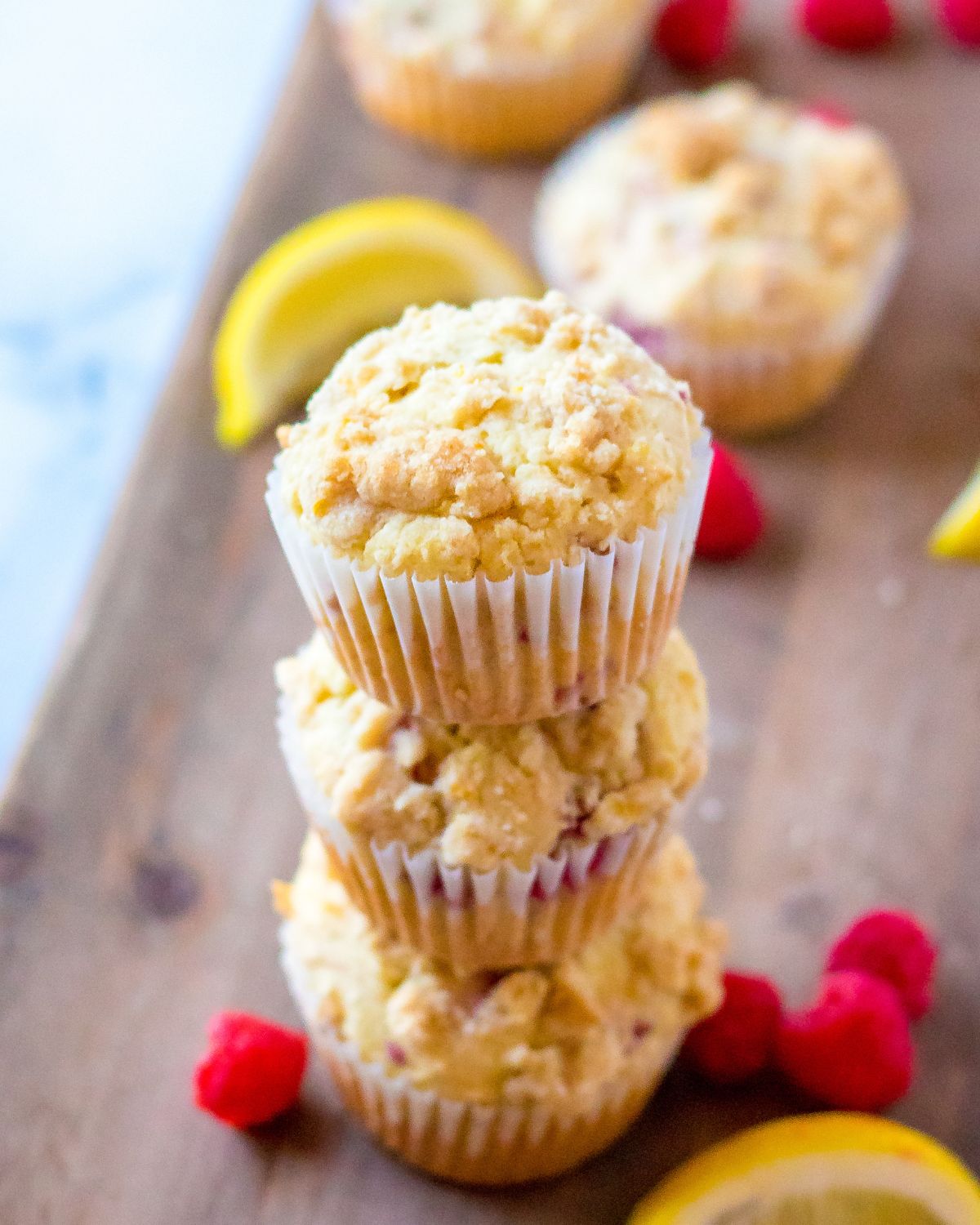 Three lemon raspberry muffins stacked up on a table.