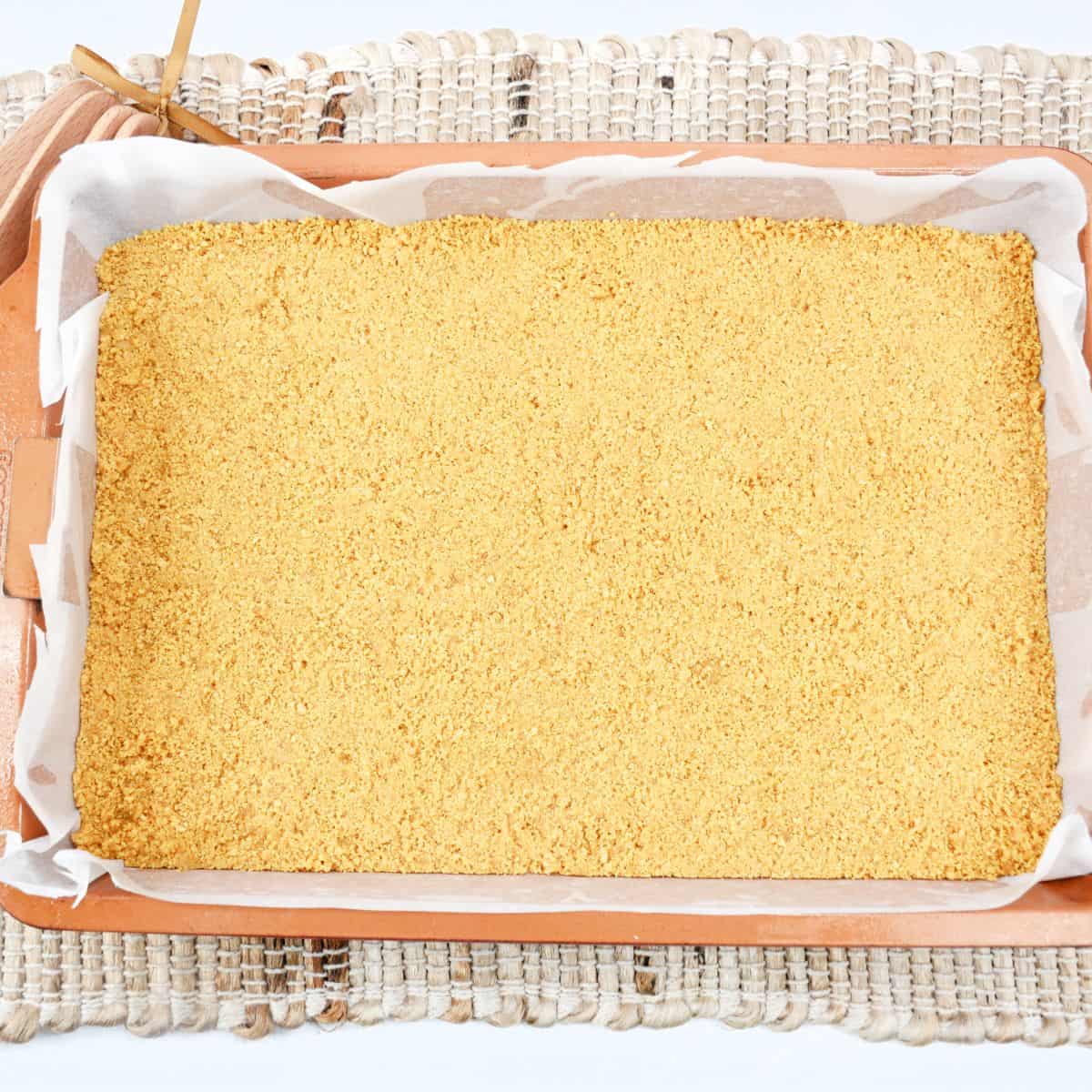 A graham cracker crust in a baking pan. 