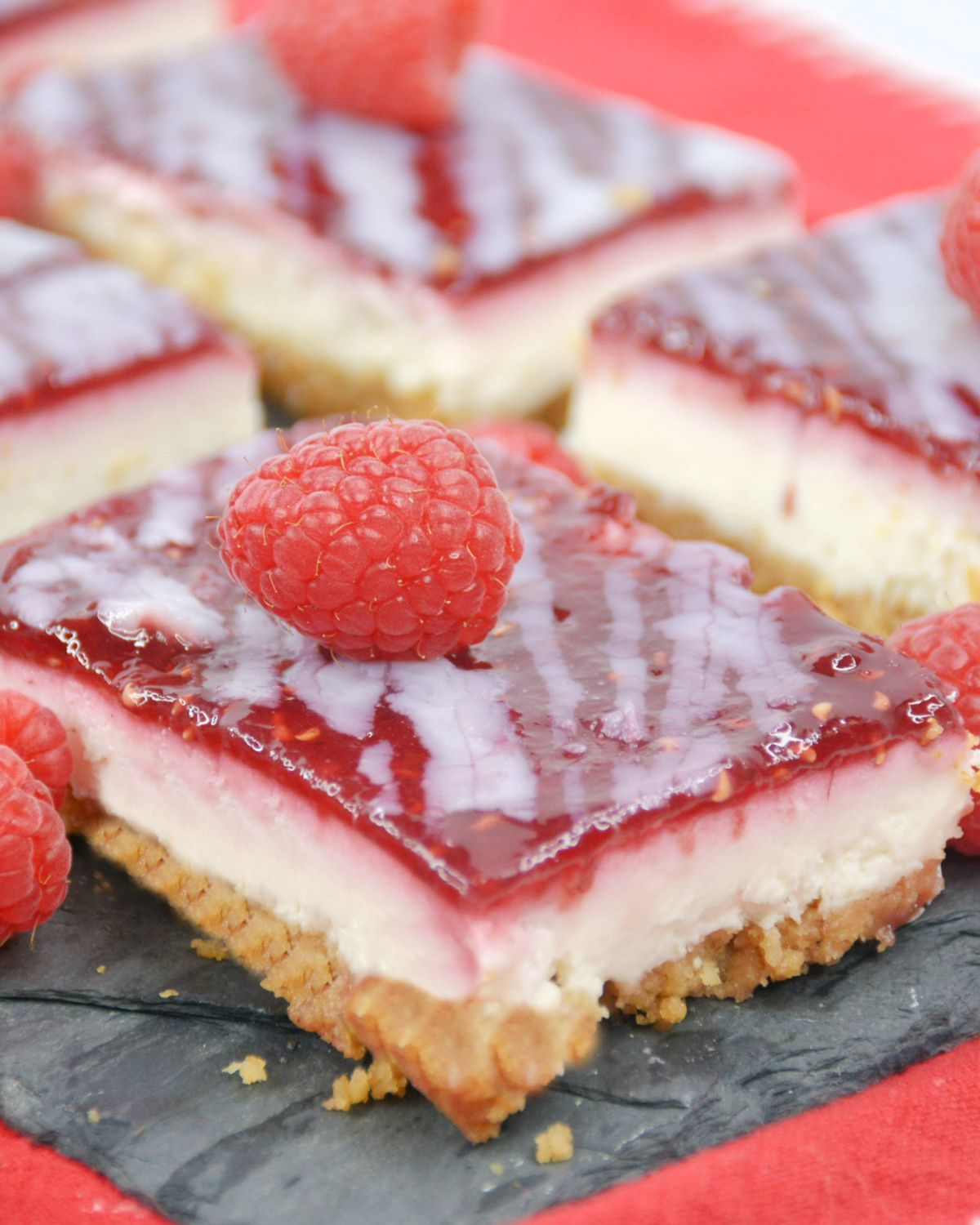 Raspberry white chocolate bars with a raspberry glaze on a black slate.