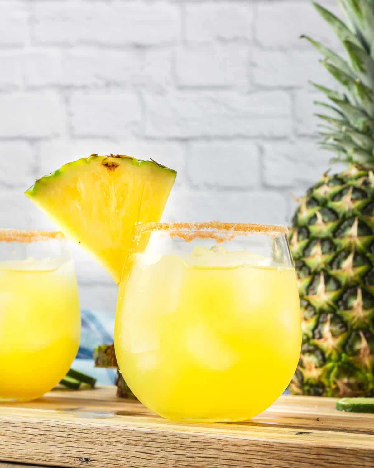 A spicy margarita in a glass trimmed with spicy seasoning and a pineapple.