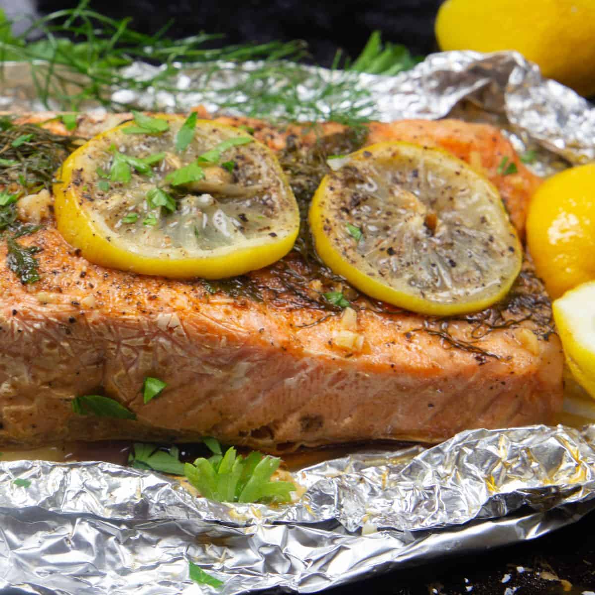 Foil wrapped salmon topped with hervs and lemon.