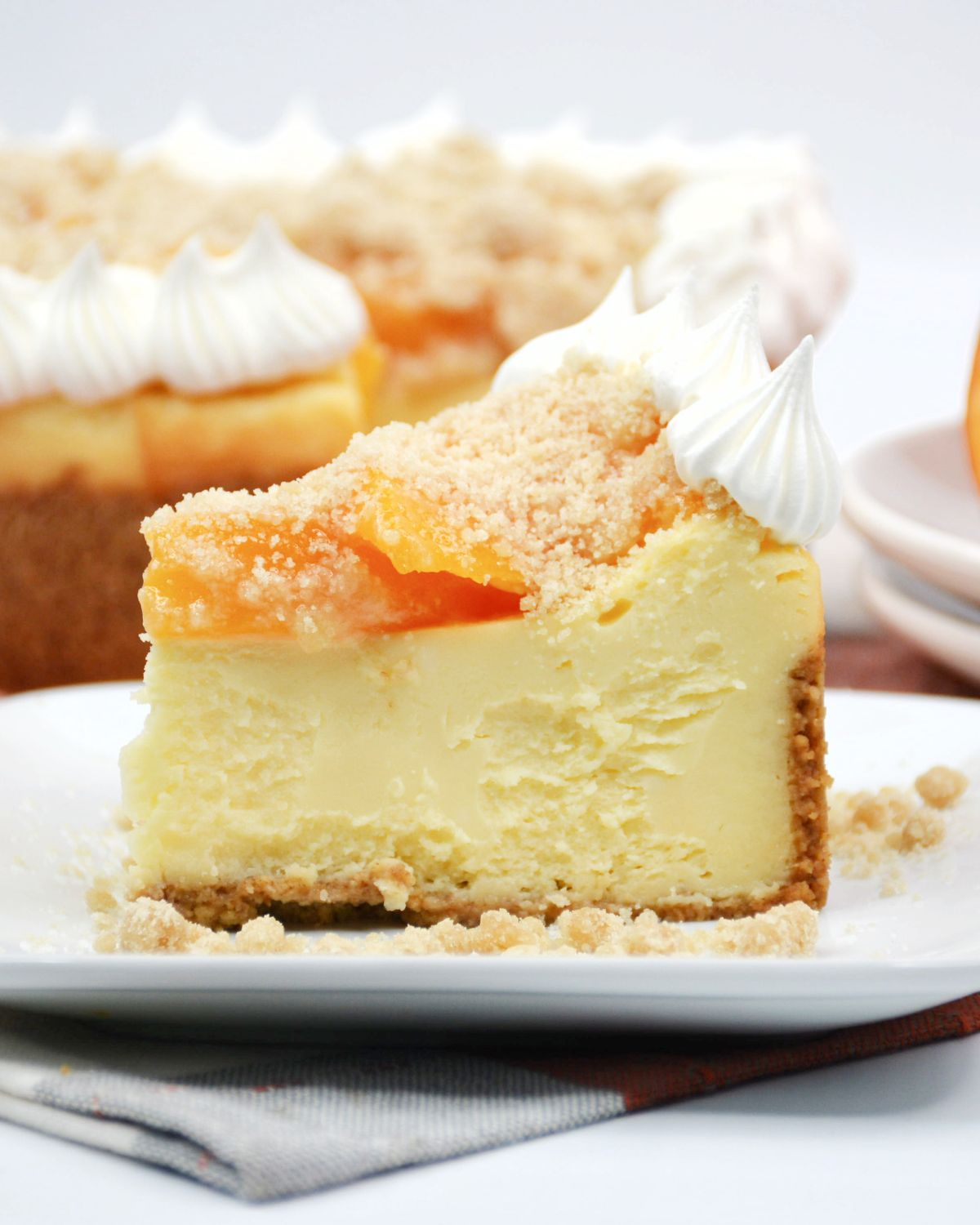 A slice of cheesecake topped with peach cobbler.