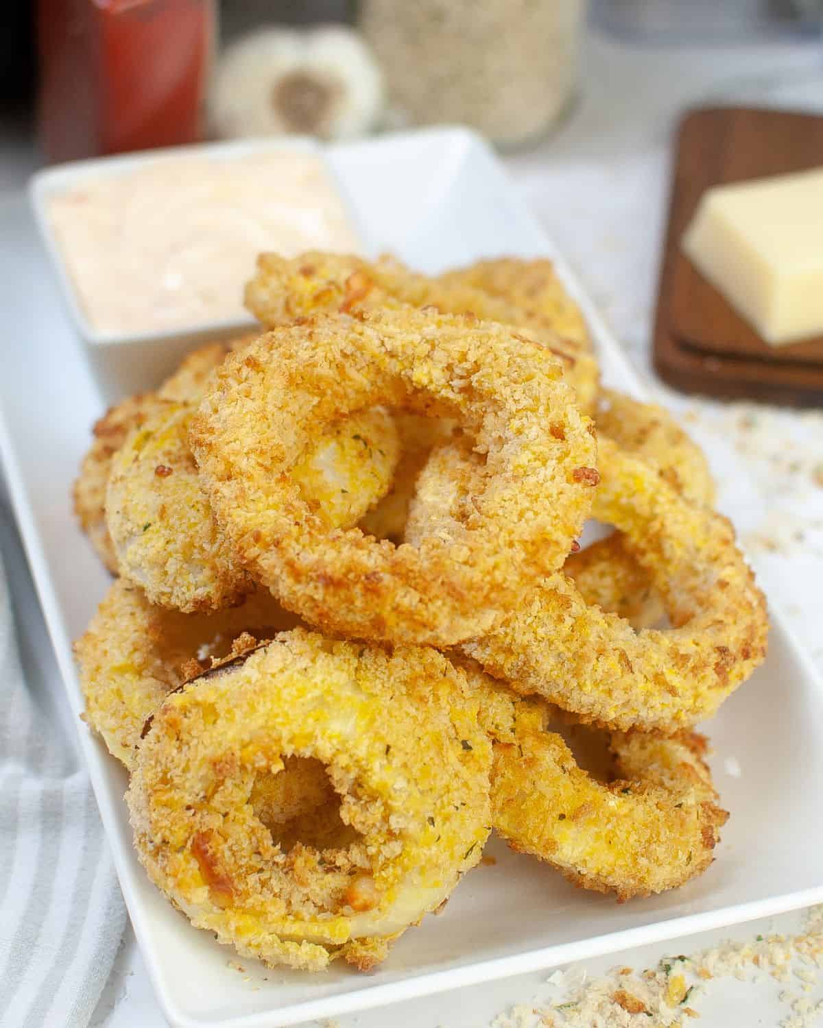 A plate of crispy onion rings made in the air fryer stuffed with cheese.