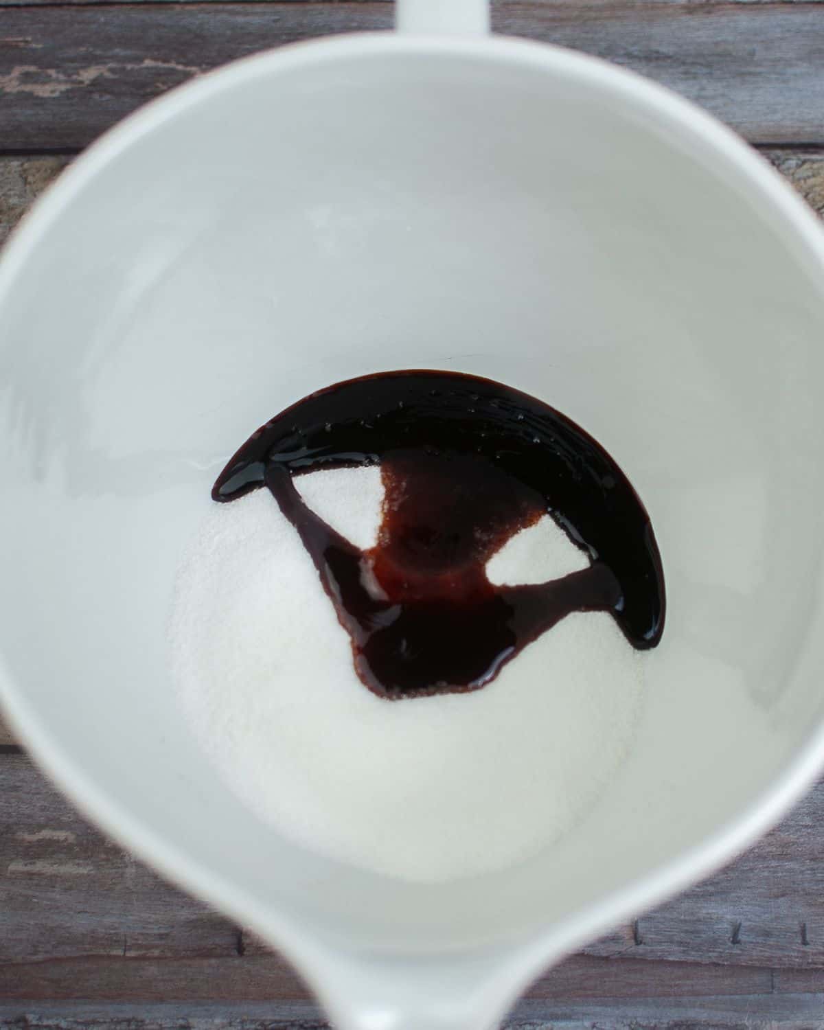 A large mixing bowl with white sugar and molasses to make light brown sugar.