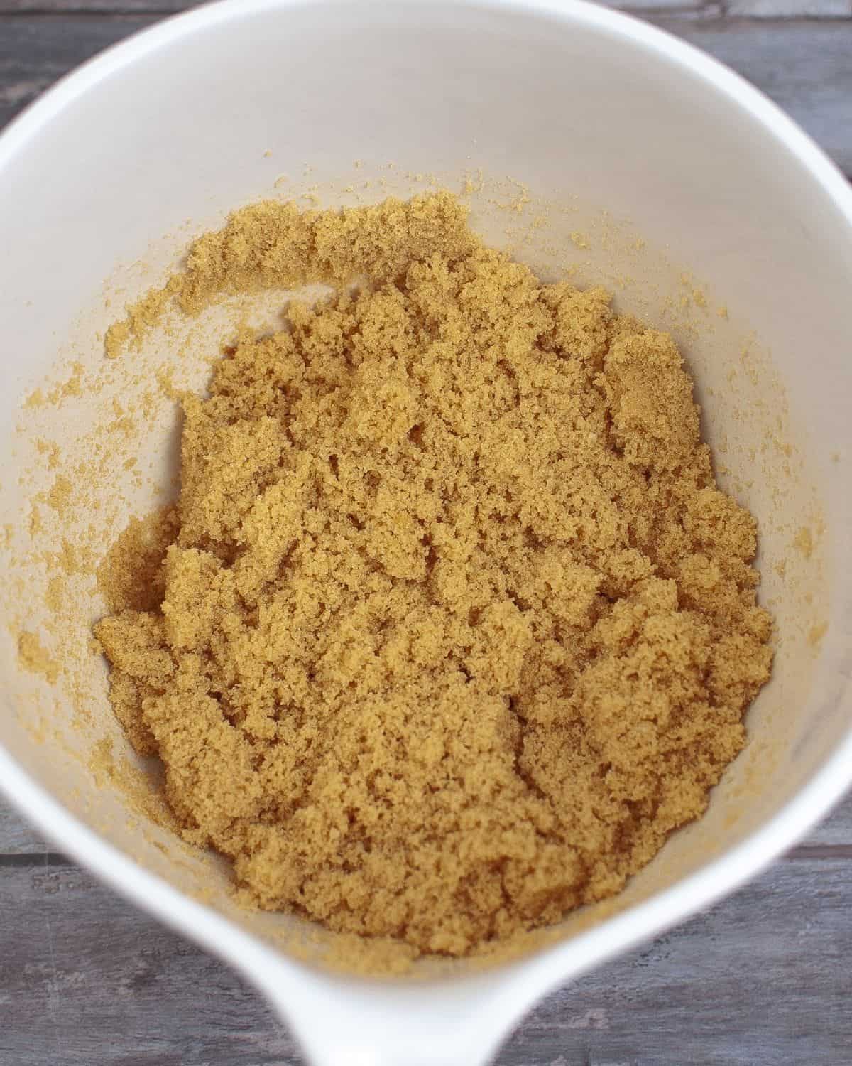 A large white mixing bowl with a combination of molasses and white sugar to make homemade brown sugar. 