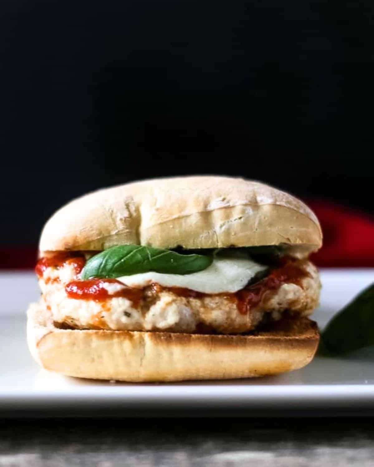 A chicken parm burger topped with mozzarella on ciabatta bread.