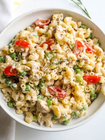 A cold tuna and pasta salad with tuna, pasta, tomatoes, and peas.