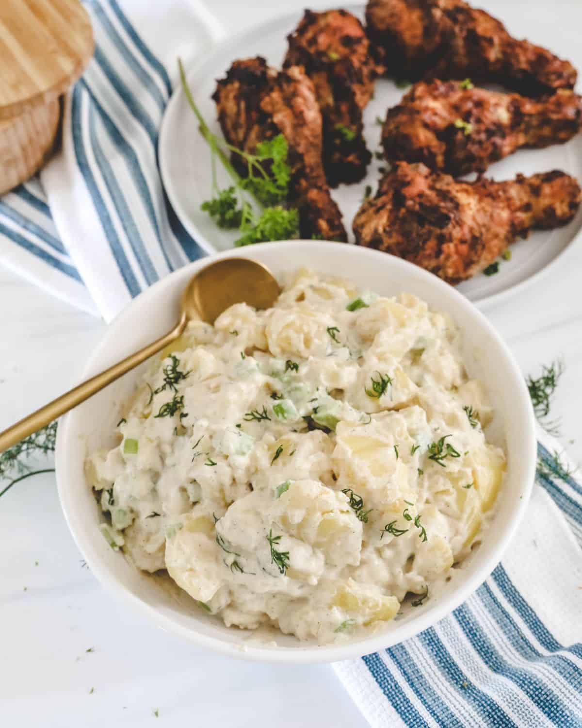 A white bowl with simple potato salad made with mayonnaise and sour cream, no eggs.