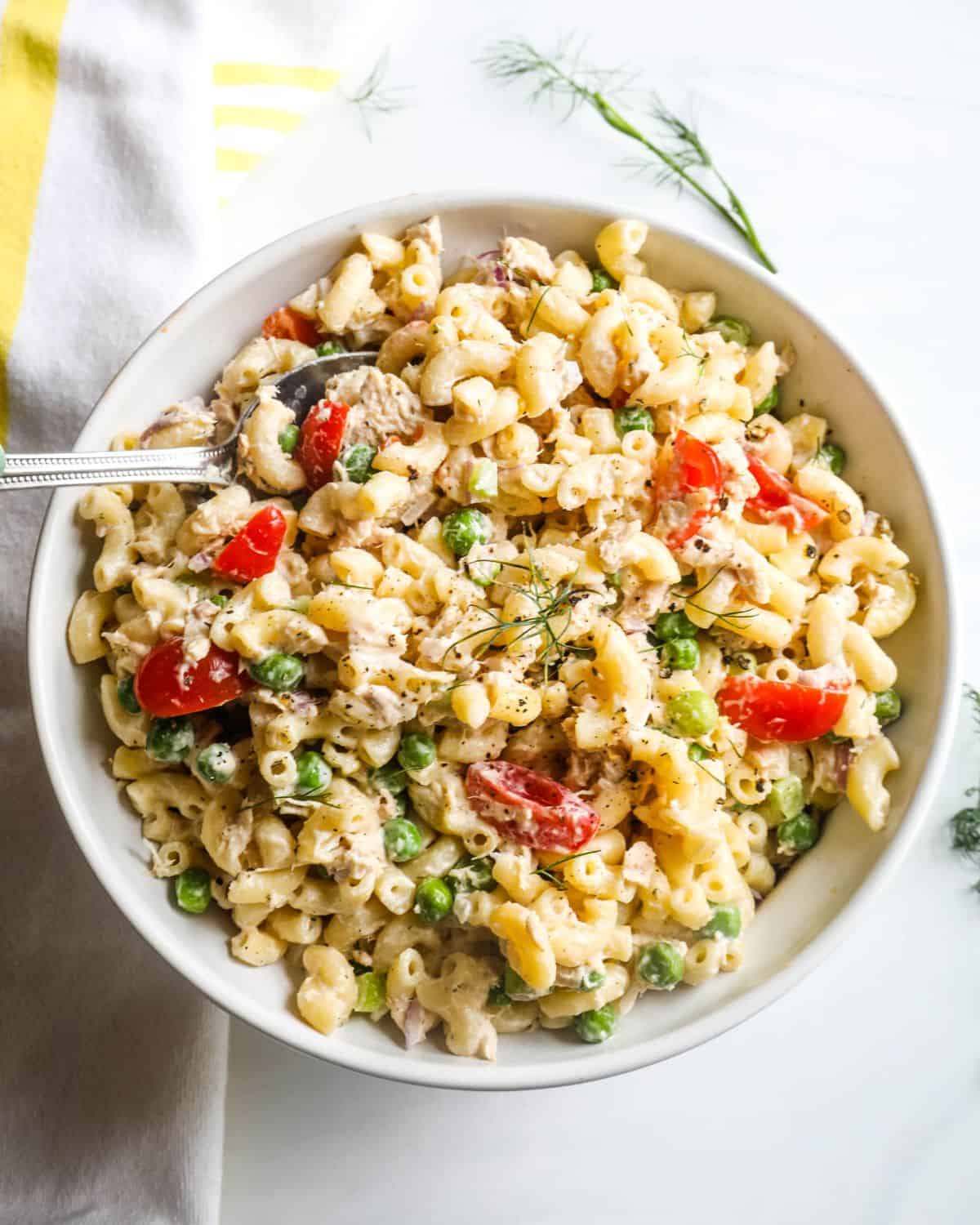 Tuna Macaroni salad with tomatoes, and peas in a creamy dressing topped with dill.