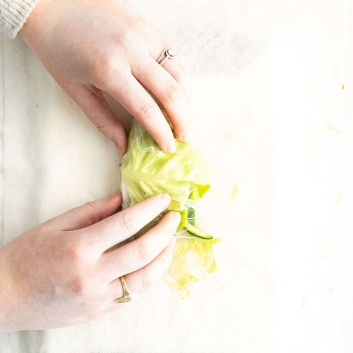 Folding up a vegetarian spring roll made with avocado and rice noodles.