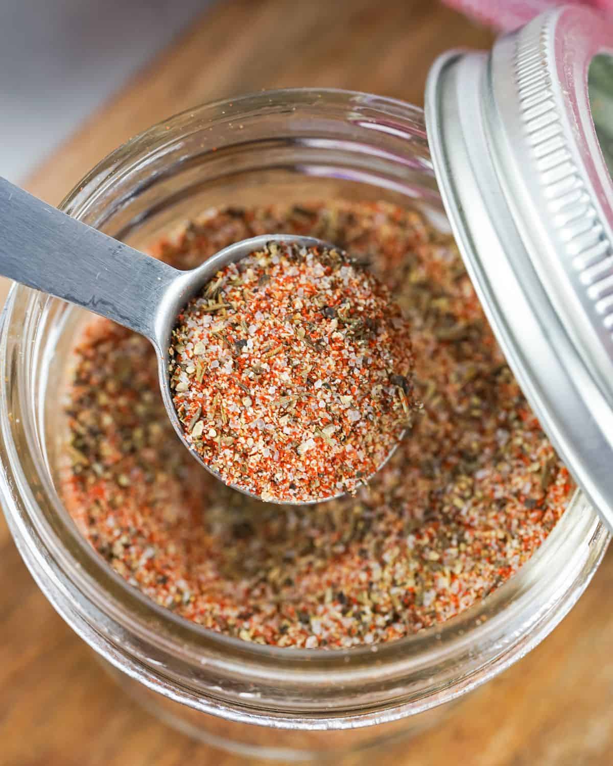 Homemade steak seasoning recipe in a mason jar with a spoon in the steak rub. 