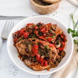 Chicken cacciatore made in the instant pot in a white bowl with mushrooms and peppers.