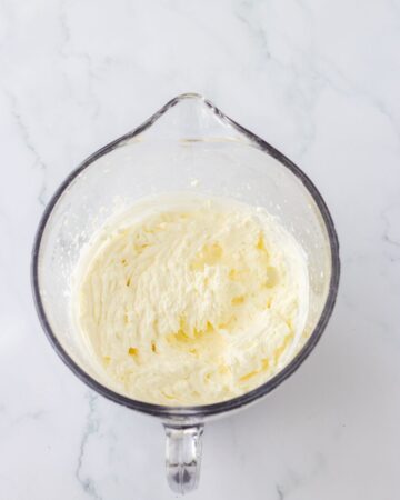 A glass measuring cup with whipped cream whipped for a strawberry pie