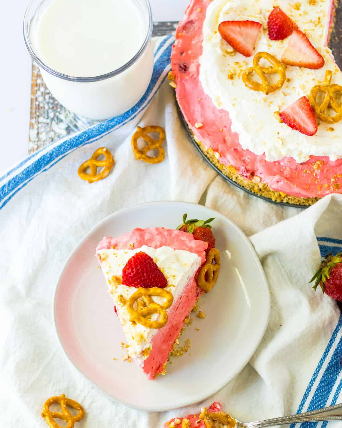 A slice of strawberry no bake pie with the remaining pie behind the plate.