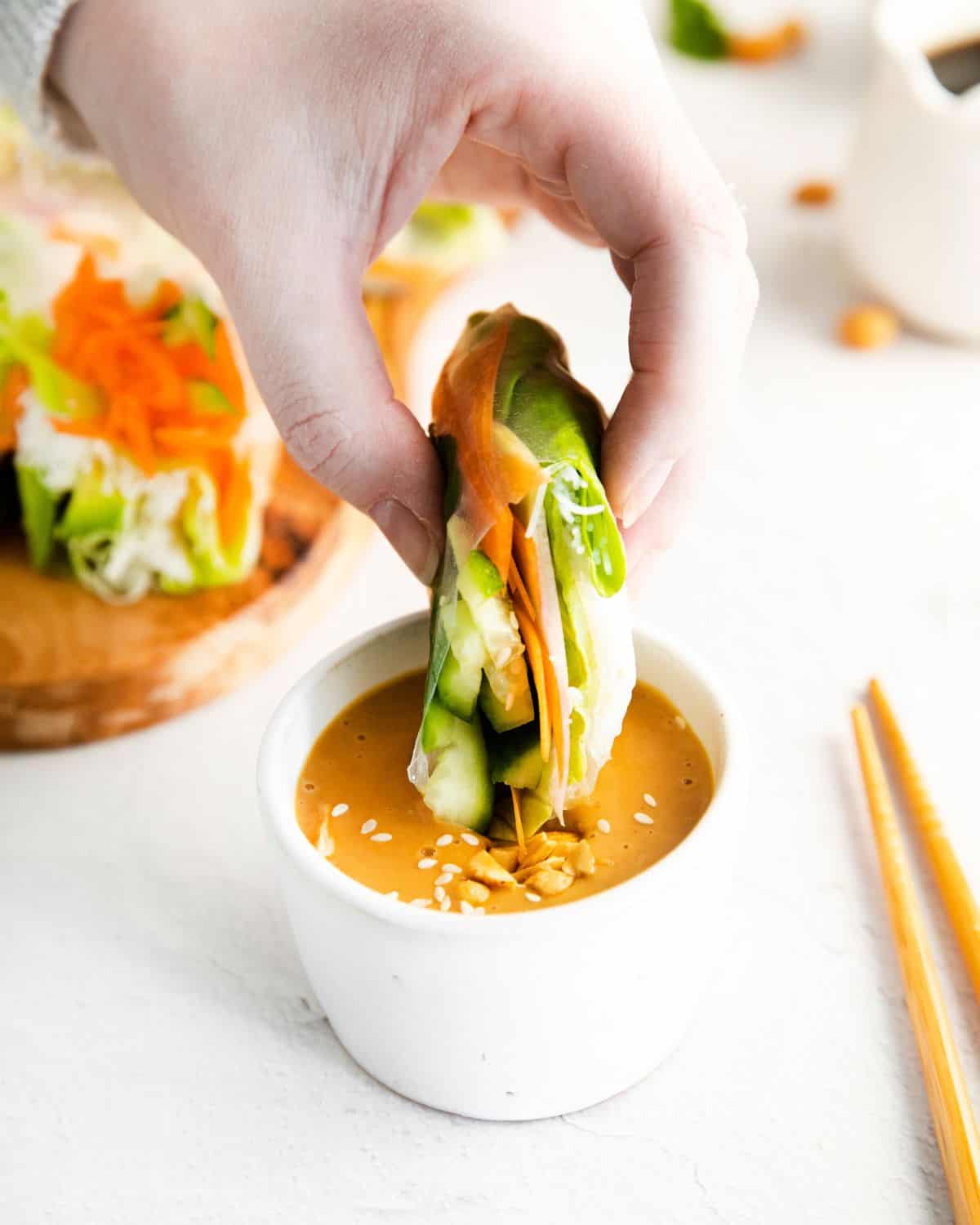 Spring rolls are dipped into a peanut sauce.