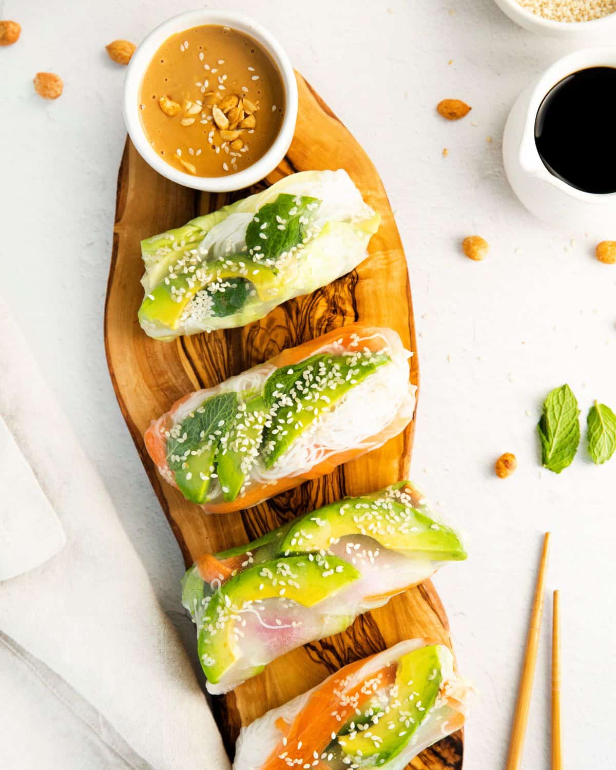 Spring rolls made with avocado and rice noodles on a platter with peanut sauce. 