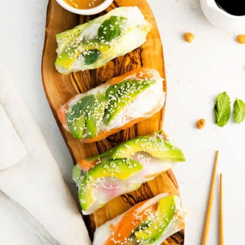 A wooden block with vegetarian avocado spring rolls on the platter.