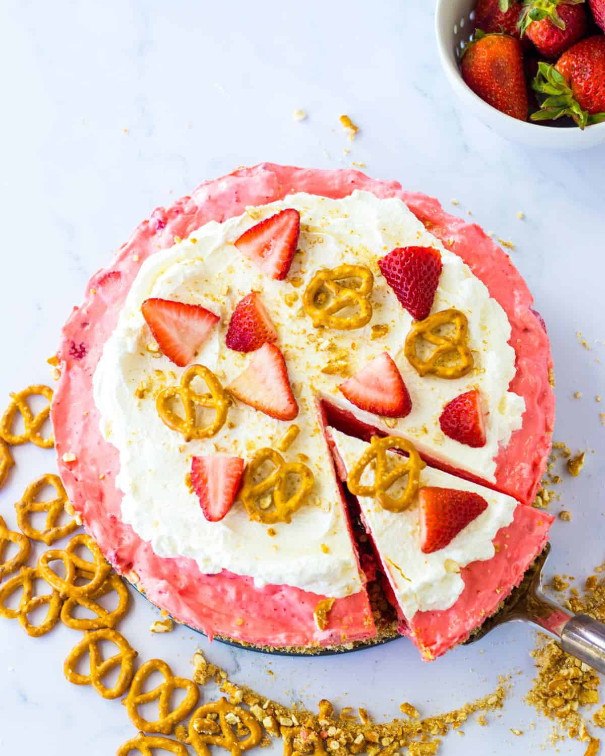 An overhead view of a no bake strawberry pie topped with sliced strawberries and pretzels.