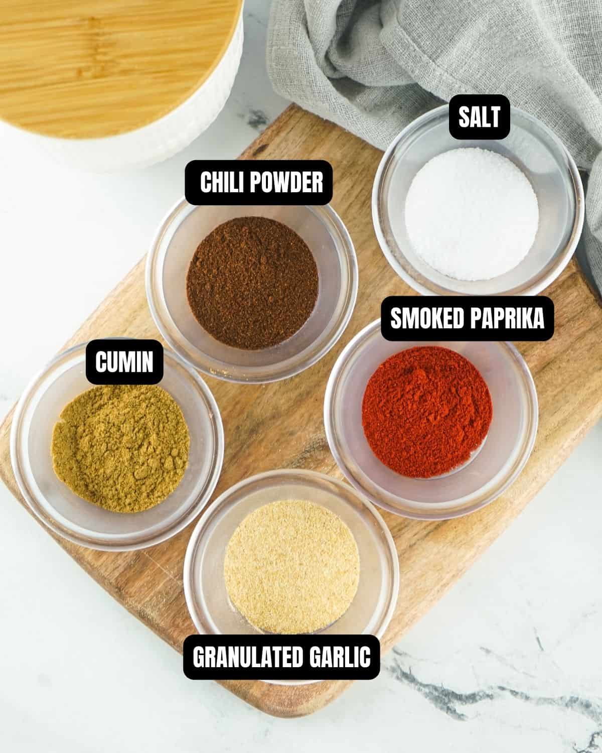 Ingredients to make fajita seasoning in glass bowls with text overlay. 