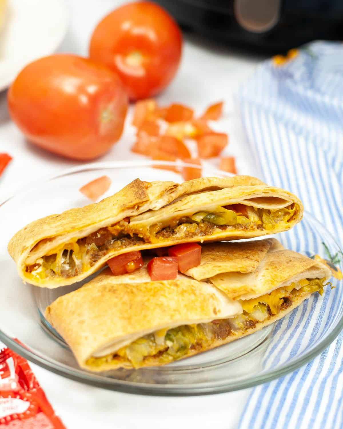 Air fryer crunch wrap supreme with chopped tomatoes on top of the wrap. 