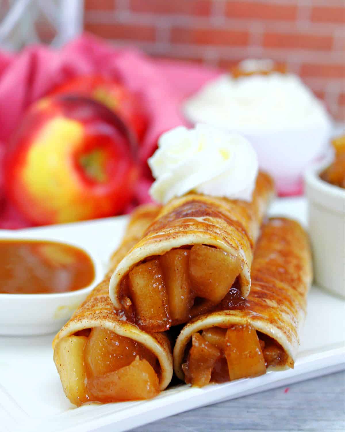 Apple pie taquitos with cinnamon sugar sprinkled on top with a caramel drizzle and ice cream.