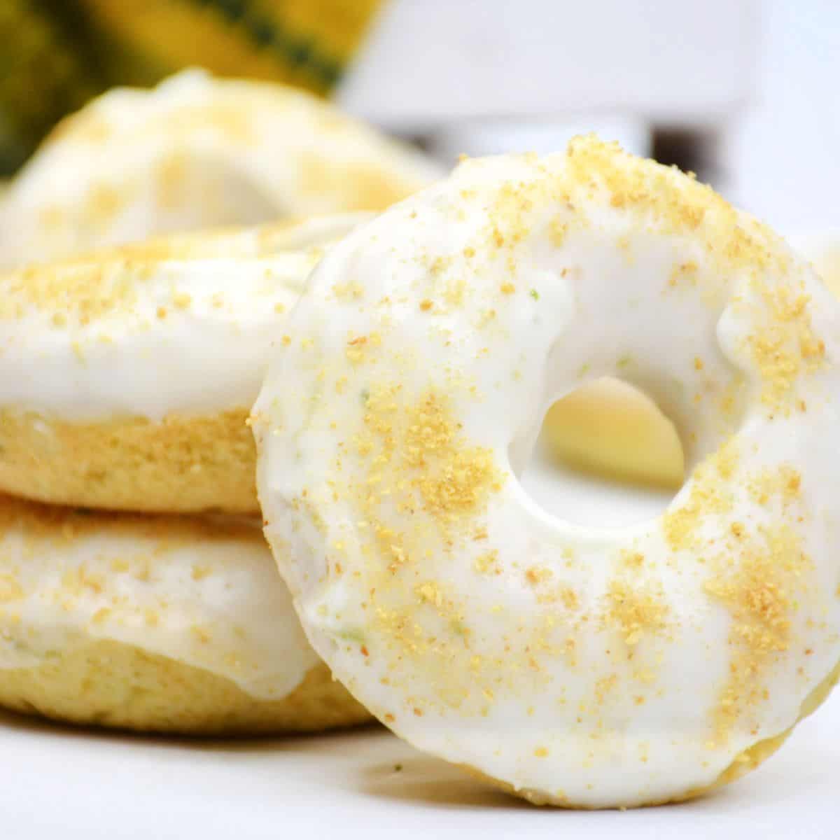 Key lime donuts with a lime glaze stacked up on a plate.