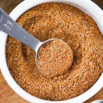 Fajita seasoning spice mix in a white bowl with a measuring spoon in it.