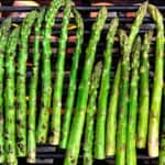 Asparagus over an open fire to be grilled.