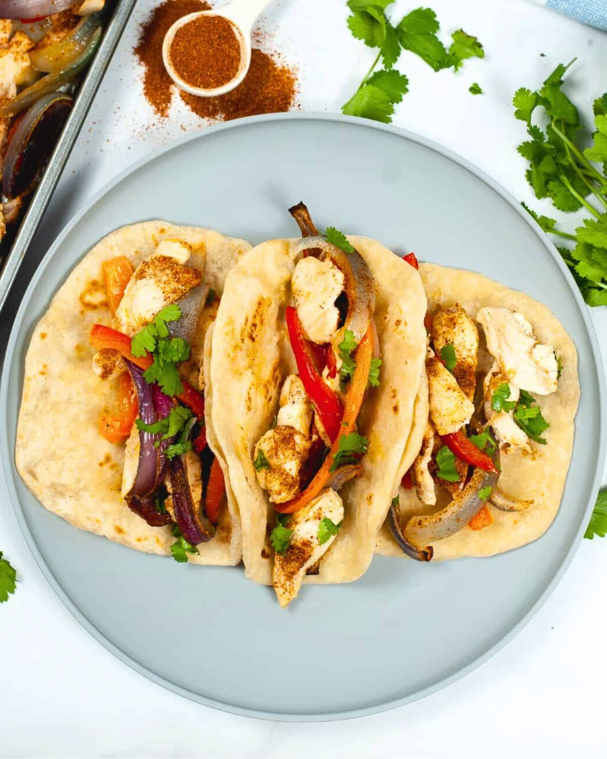 A large plate filled with tortillas and chicken fajitas with peppers and onions. 