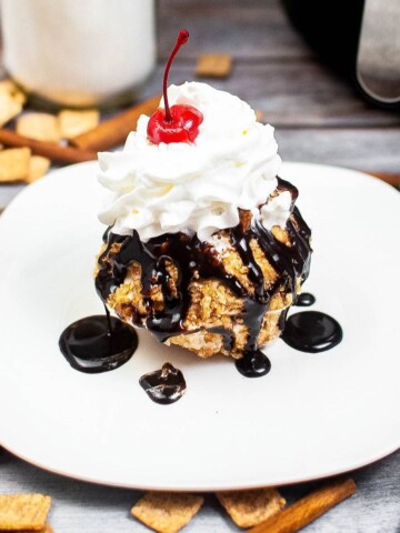 Fried ice cream on a plate with chocolate and whipped cream.