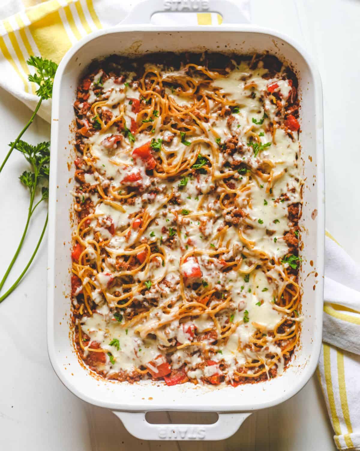 A casserole dish with baked spaghetti in a ground beef tomato sauce. 