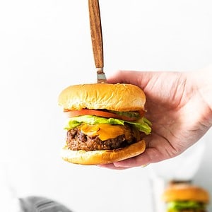 BBQ burger in a bun topped with lettuce, tomato, and cheese.