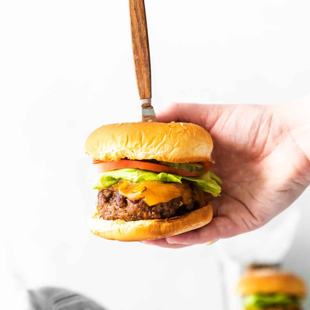 BBQ burger in a bun topped with lettuce, tomato, and cheese.