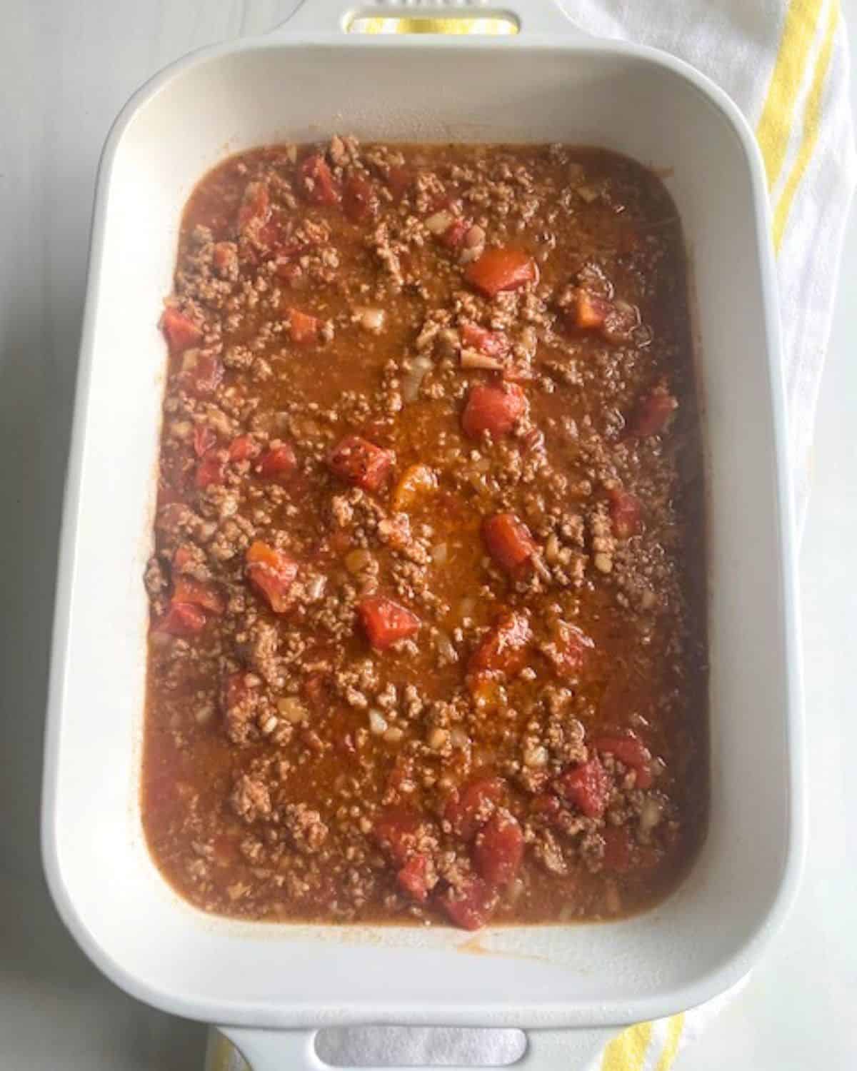 A large casserole dish with layers of spaghetti and meat sauce for a baked spaghetti casserole.