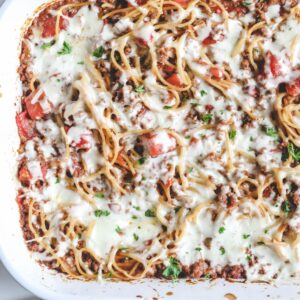 A casserole dish with baked spaghetti and meat sauce topped with cheese.