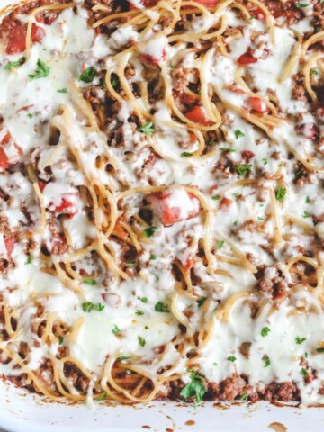A casserole dish with baked spaghetti and meat sauce topped with cheese.