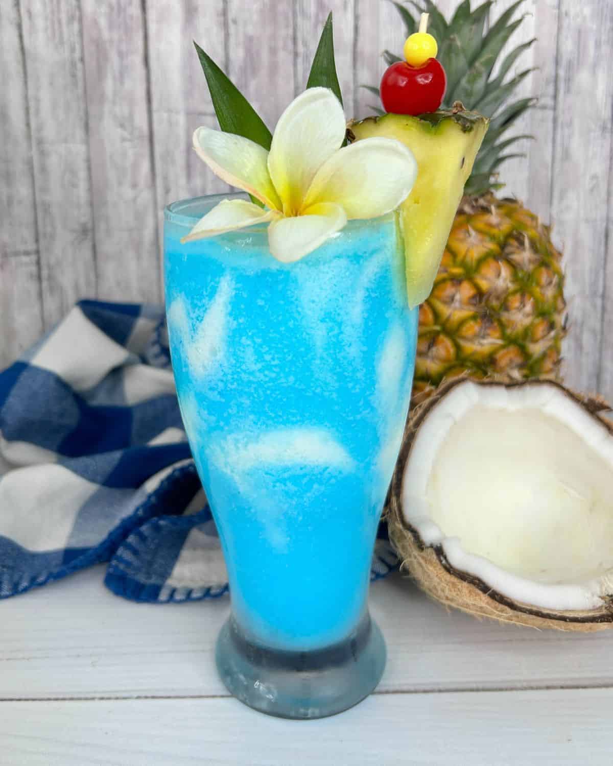 A large clear glass with frozen blue pina colada. 