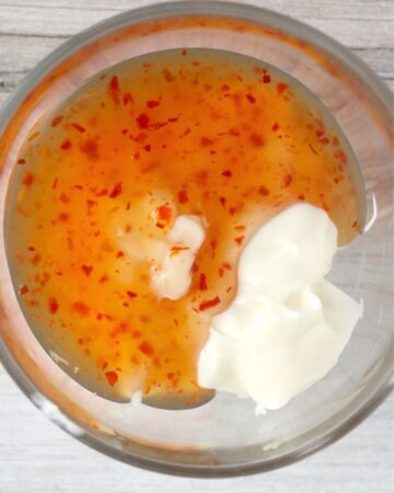 A glass bowl with mayonnaise and sweet chili sauce.