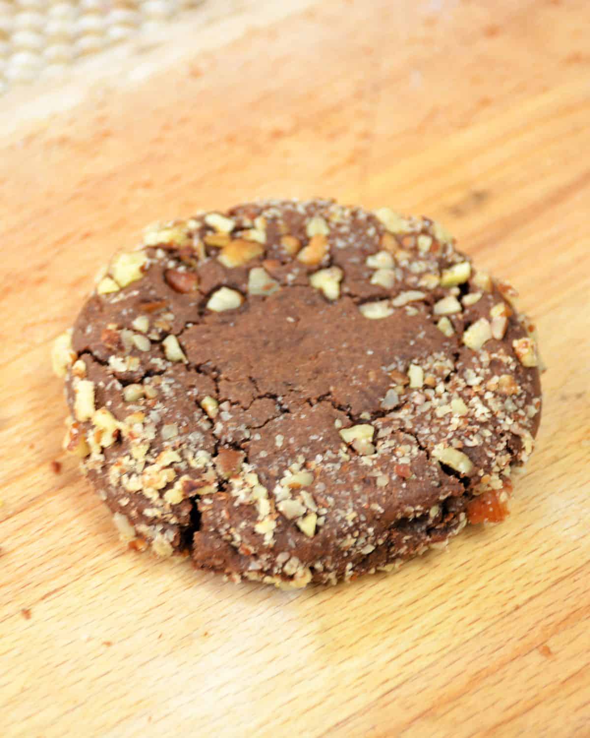 A turtle cookie, a copycat crumbl cookie on a wooden platter. 