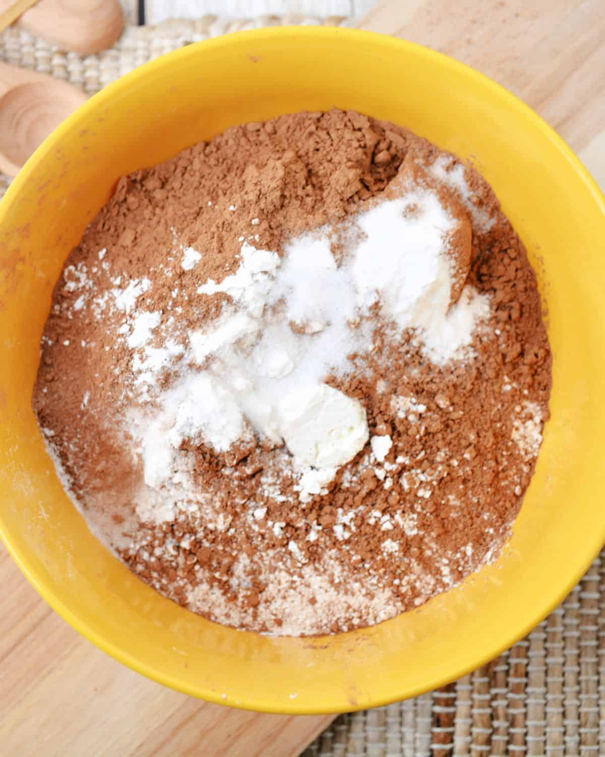 A mixing bowl with cocoa powder, wet and dry ingredients to make copycat Crumbl turtle cookies.