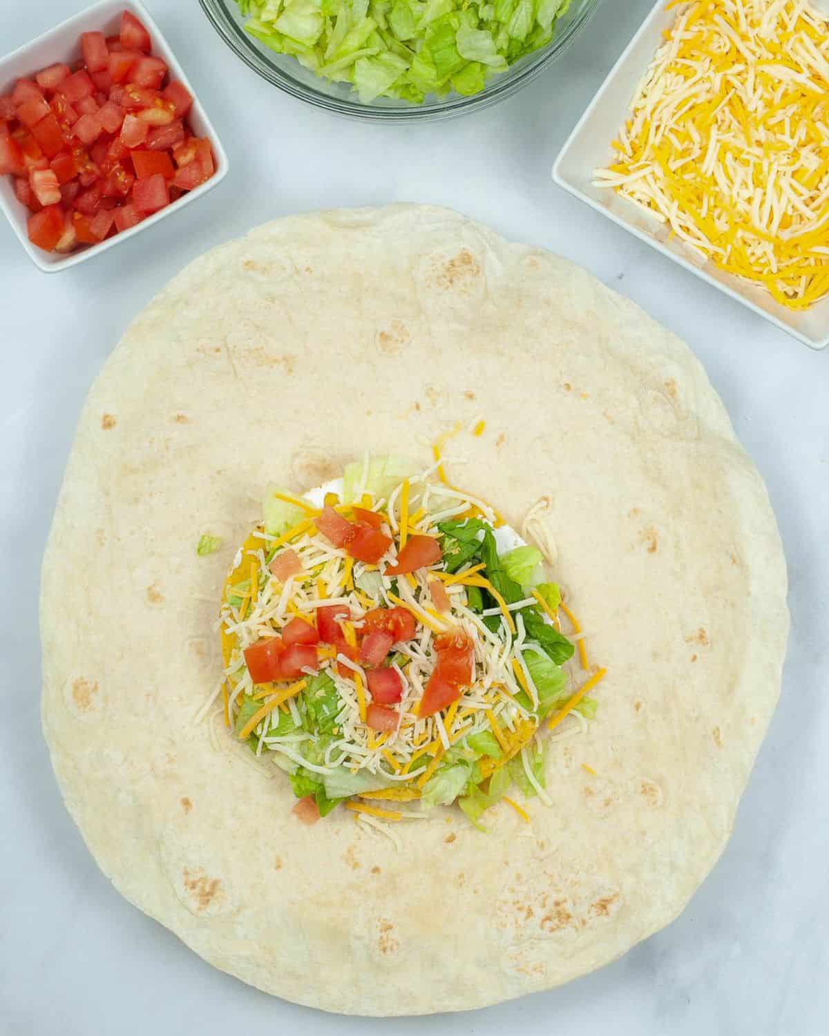Crunchwrap supreme steps to make with lettuce and tomatoes on top of the beef and sour cream.