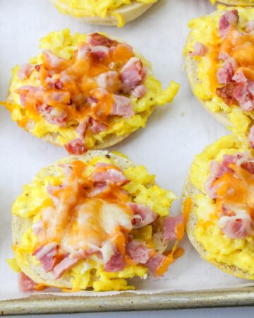 Baked breakfast pizza bagels topped with ham and eggs.