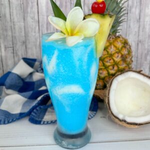 Frozen pina colada made with blue curacao and a flower and pineapple in the glass.