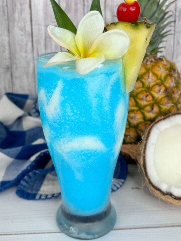 Frozen pina colada made with blue curacao and a flower and pineapple in the glass.