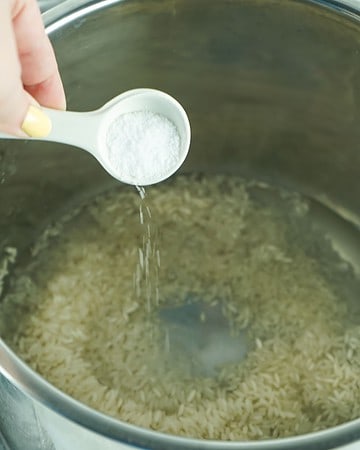 Salt being added to the vessel of the instant pot for white rice.