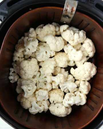 An air fryer with cauliflower florets.