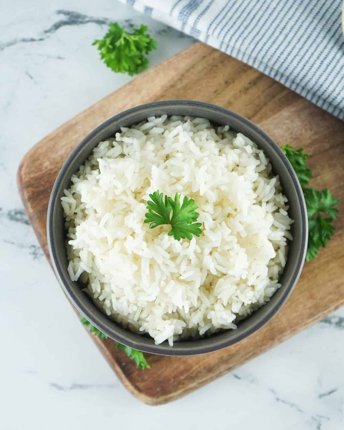 White rice that was cooked in the Instant pot in a bowl with fresh parsley.