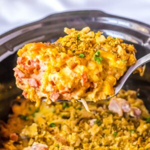 A spoon picking up crock pot chicken cordon bleu out of the pot.