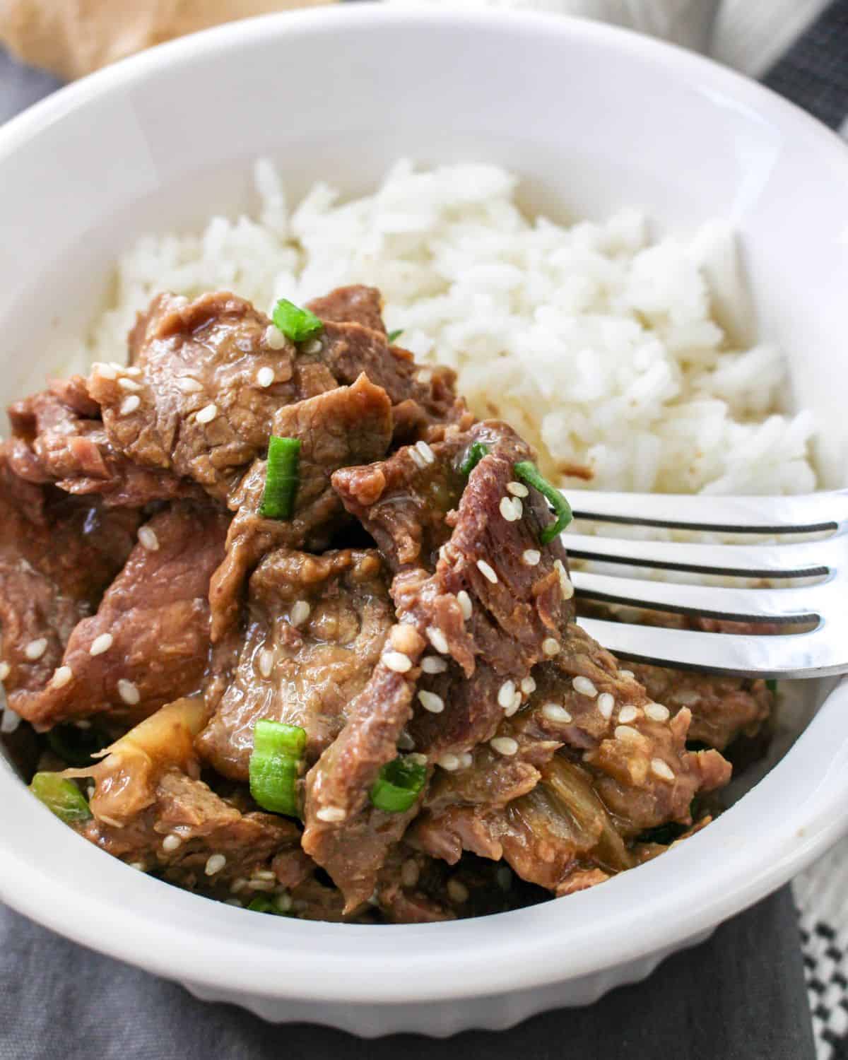 Korean beef made in the slow cooker served with rice and topped with sesame seeds.